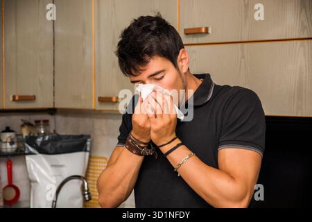 Jeune homme soufflant le nez dans les tissus Banque D'Images