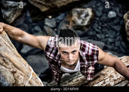 Bel homme grimpant un rocher à la rivière Banque D'Images