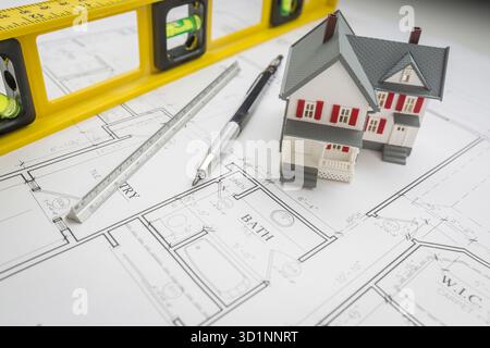 Maison modèle, niveau, crayon et règle reposant sur les plans de la maison Banque D'Images