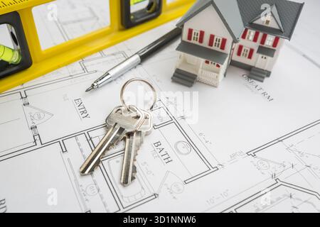 Maison, niveau de construction, crayon et clés reposant sur les plans de la maison Banque D'Images