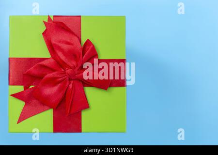 Un cadeau vert avec un ruban rouge et un arc Banque D'Images