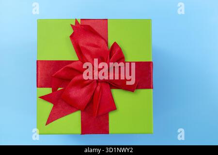 Un cadeau vert avec un ruban rouge et un arc Banque D'Images