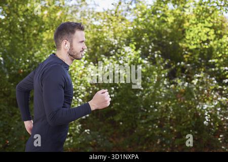 Portrait d'un runner listening to music on headphones lors de l'exécution en plein air Banque D'Images