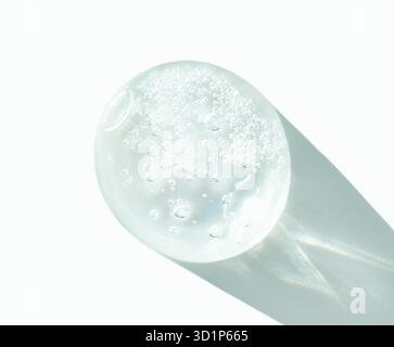 Sphère de verre transparente avec des bulles projetant l'ombre sur la surface blanche dans la lumière naturelle. Banque D'Images