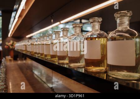 Une vue en perspective à angle bas d'une longue rangée de bouteilles d'apothicaire en verre remplies d'huiles de parfum jaunes dans un magasin de parfums de luxe. Les bouteilles, qui Banque D'Images