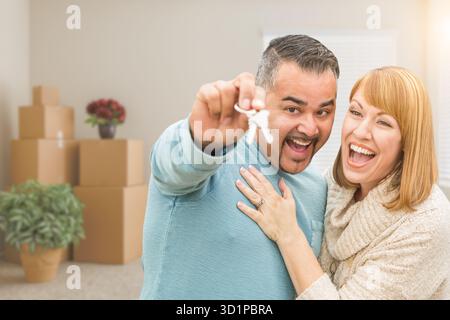 Couple tenant des clés de maison à l'intérieur de la pièce vide avec des boîtes mobiles Banque D'Images