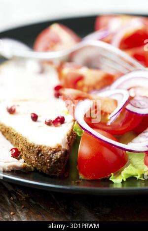 Ensemble de porc cuit au four dans une assiette avec salade de légumes sur une vieille table en bois Banque D'Images