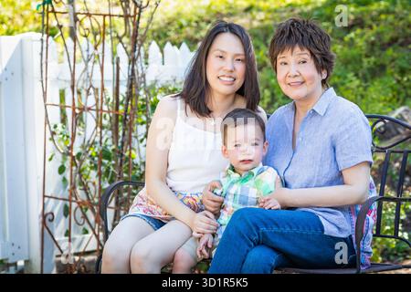 Grand-mère chinoise, fille et enfant de race mixte assis sur le banc à l'extérieur Banque D'Images