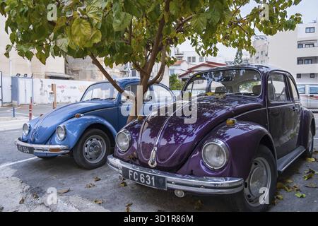 Larnaca, Chypre - 8 février 2022: Un puprle et un bleu magnifiquement entretenu chrome peint classique Volkswagen Beatle voitures garées dans un parc de rue u Banque D'Images