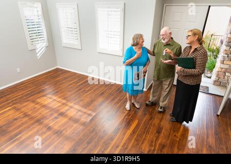 Agent immobilier féminin remettant de nouvelles clés de maison au couple adulte senior dans la nouvelle maison Banque D'Images