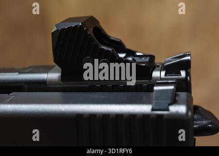 Macro gros plan détaillé d'un viseur collimateur à micro point rouge noir moderne monté sur une glissière de pistolet semi-automatique. Banque D'Images