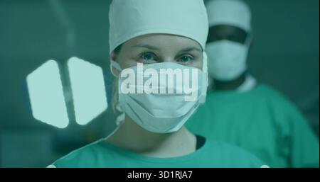 Chirurgien féminin opérant dans les gommages verts et masque effectuant la chirurgie à l'hôpital OU, avec OU lampe Banque D'Images