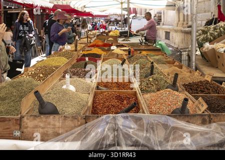 Syrakus, Sizilien - Italie - 04-09-2025 : un étal en bois sur le marché de Syrakus expose une grande variété d'herbes séchées colorées et d'épices sous une boîte Banque D'Images