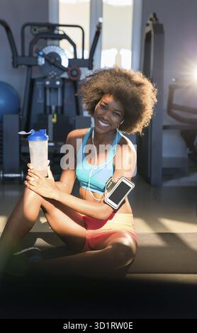Portrait d'une femme en forme épuisée se relaxant après l'entraînement avec des poids libres, charmante fille ayant un repos après la formation de fitness au gymnase Banque D'Images