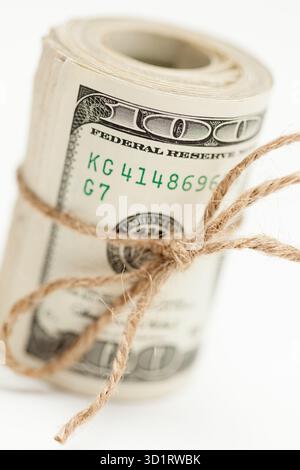 Rouleau de billets de cent dollars attaché dans la ficelle de toile de jute sur blanc Banque D'Images