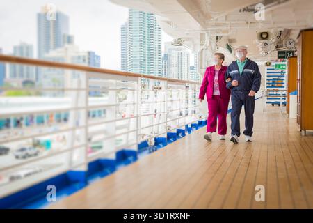 Couple senior marchant le long du pont des navires de croisière passagers portant des masques faciaux Banque D'Images