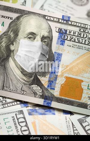 Billet de cent dollars avec masque médical sur le visage de Benjamin Franklin Banque D'Images
