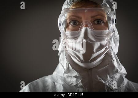 Travailleuse médicale portant un masque facial de protection et de l'équipement sur fond sombre Banque D'Images