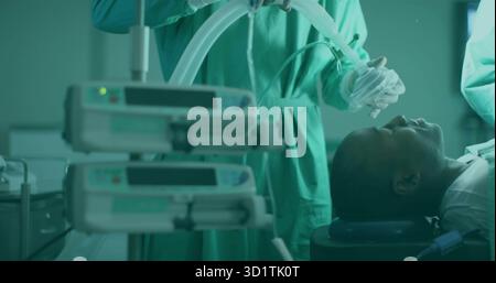 Anesthésiste dans les gommages tenant le masque d'anesthésie au-dessus du patient dans OU, avec les pompes à perfusion, copier l'espace Banque D'Images