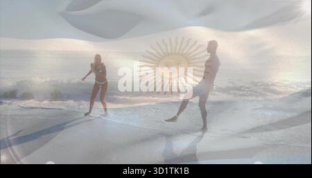 Couple debout portant un maillot de bain deux pièces et des malles au rivage, avec des vagues de l'océan, emblème du soleil Banque D'Images