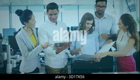 Examen de cinq professionnels collaborant autour du bureau dans un bureau moderne, avec tablette et rapports Banque D'Images