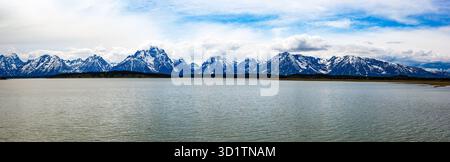 Vue panoramique sur la chaîne enneigée de Teton Ranges qui s'élève au-dessus du lac Jackson dans le parc national de Grand Teton, Wyoming, États-Unis, sous un ciel printanier spectaculaire. Banque D'Images