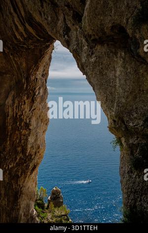Arc de roche naturel encadrant la mer Méditerranée avec un petit bateau en vue, île de Capri, Italie. Banque D'Images