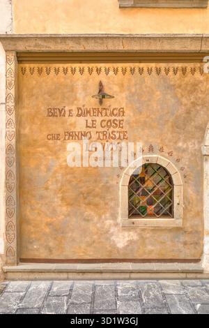 Inscription murale et fenêtre décorative en treillis dans la vieille ville de Tolmezzo, Friuli-Venezia Giulia, Italie Banque D'Images