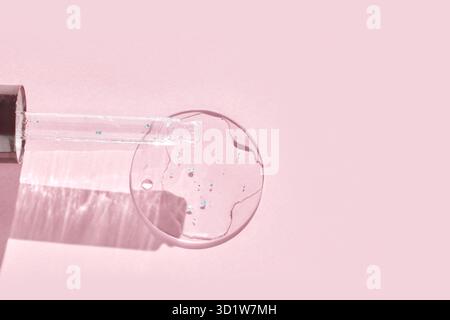 Nuance de texture de gel de sérum. Goutte transparente avec des sparkles dorés. Fond rose. Produit de soin pour le visage. Essence d'huile liquide. Éclaboussures de collagène de beauté. O Banque D'Images