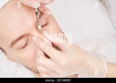 Injection au spa.Médecin mains dans des gants.Gros plan.Patient assez masculin Banque D'Images