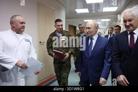 Moscou, Russie. 29 octobre 2025. Le président russe Vladimir Poutine, au centre, écoute Pavel Krainyukov, chef de l'hôpital clinique militaire central Mandryk, à gauche, alors qu'il visite l'établissement avec le ministre de la Défense Andreï Belousov, à droite, le 29 octobre 2025 à Moscou, en Russie. Les soldats de la 127e brigade de reconnaissance séparée ont donné à Poutine des icônes religieuses avec des éclats d'obus et des marques de balles pour son anniversaire. Crédit : Vyacheslav Prokofyev/Kremlin Pool/Alamy Live News Banque D'Images
