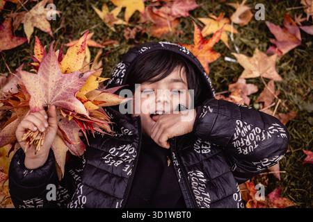 vue supérieure d'une fille allongée au milieu des feuilles d'automne rouges et jaunes Banque D'Images