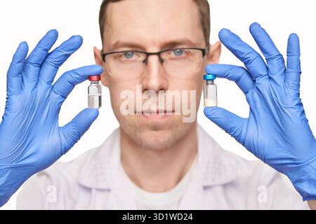 Personne masculine dans des gants bleus tient des bouteilles de vaccin. Pharmacie de drogues injectables Banque D'Images