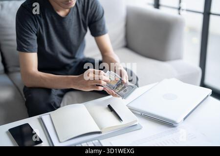 Homme calculer argent billets de banque finances épargne économie maison payer factures impôts financiers à la maison Banque D'Images