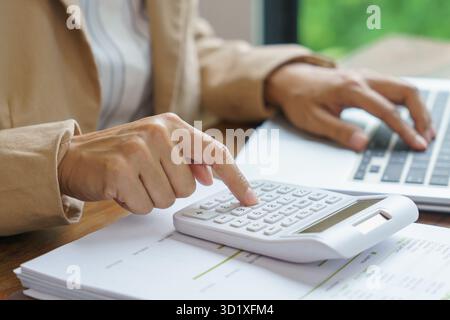 Femme d'affaires calculant l'état financier sur la calculatrice déclaration d'impôt sur le revenu en ligne et paiement. Banque D'Images