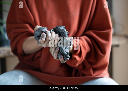 Femme céramiste se coince de l'argile à pétrir tout en travaillant au studio de poterie Banque D'Images