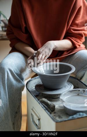 Maître en céramique créant du grès fait à la main sur la roue en studio, formant de l'argile en forme Banque D'Images