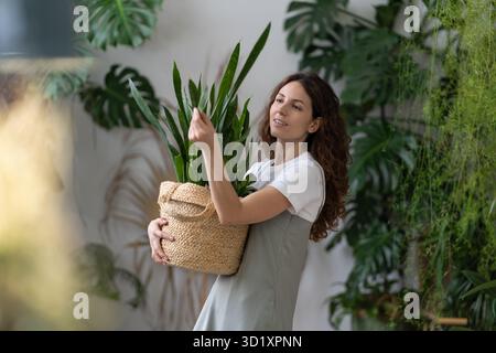 Femme jardinier prenant soin de l'usine de serpent tout en travaillant dans le jardin à la maison Banque D'Images