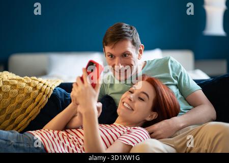 Homme et femme regardant la vidéo sur smartphone. Repos, détente, bonne qualité agréable passe-temps confortable Banque D'Images