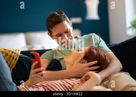 Femme couchée sur les genoux de l'homme. Guy embrasse la fille tout en se relaxant sur le canapé. Intimité, proximité, amour, soins Banque D'Images