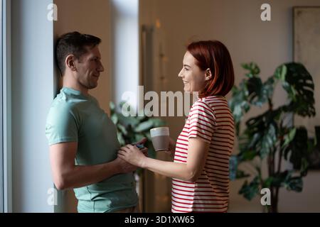 Heureux couple caucasien d'âge moyen se tenant la main se regardant l'un l'autre célébrant l'anniversaire. Banque D'Images
