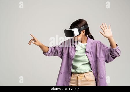 Femme dans des lunettes virtuelles joue au jeu vidéo points index sur l'espace de copie sur fond gris. Banque D'Images