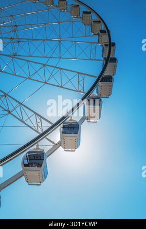 Gondoles et rayons d'une grande grande roue silhouette sur ciel bleu ensoleillé Banque D'Images