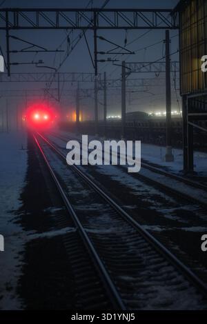 Feux vides de chemin de fer et de voie ferrée avec signal rouge dans le brouillard la nuit. Temps sombre Banque D'Images