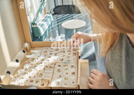 Femme adulte caucasienne créant des bijoux en résine avec des éléments botaniques dans un atelier d'artisanat. Banque D'Images