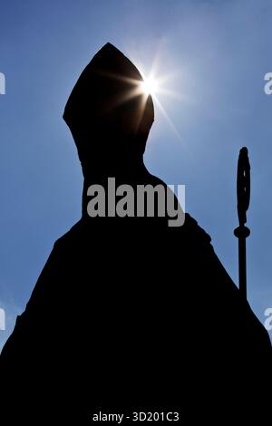 Évêque catholique anonyme avec mitre et crosier comme silhouette en contre-jour, photo symbolique Banque D'Images