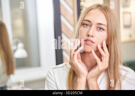 Jeune femme caucasienne avec de longs cheveux blonds et des yeux bleus en intérieur Banque D'Images