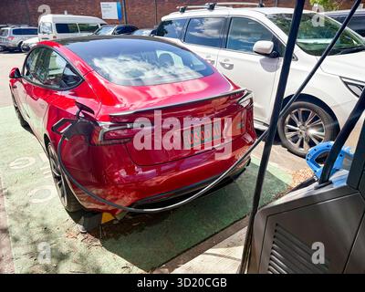 Véhicule électrique Tesla Model 3 rouge 2024 chargé sur un chargeur Jolt public à Mona Vale, Sydney, Australie Banque D'Images