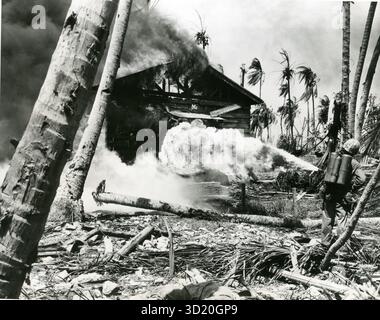 La mort enflammée entre les mains du Cpl Norman R. Burkhalter de Buhl, Idaho, détruit ce bâtiment sur l'île de Namur. Les lance-flammes ont été utilisés avec une grande efficacité lors de l'invasion de l'atoll de Kwajalein. Notez le soldat japonais mort au premier plan. Banque D'Images