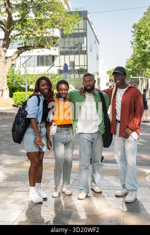 Heureux jeune groupe multiculturel d'amis se tiennent ensemble, embrassant et souriant à la caméra sur la marche Banque D'Images